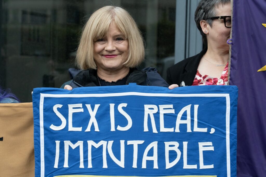 Sex is real immutable banner held by a smiling lady